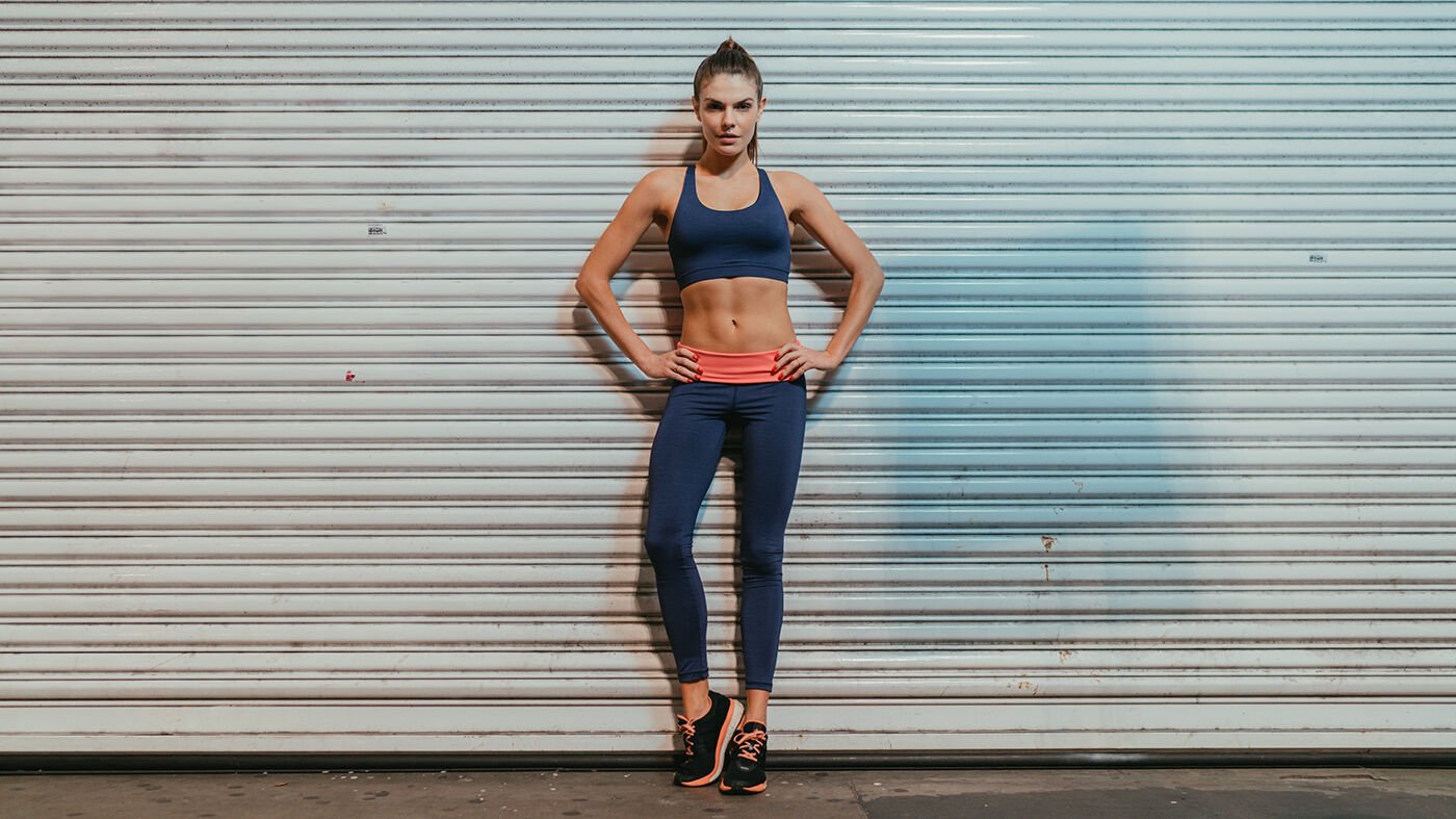Alekta sportswear: a model in leggings and a sports top against a steel shutter at night