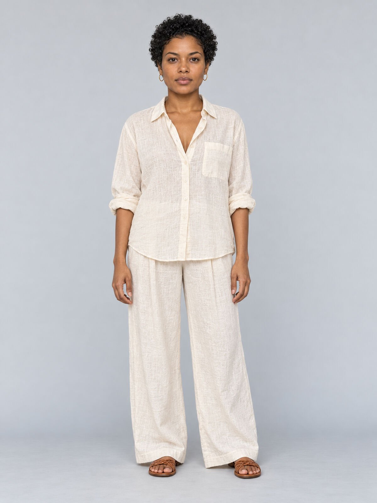 E-commerce front view of a woman in a linen shirt and wide trousers on a pale blue ground