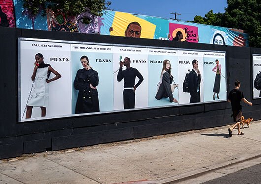 A row of Prada posters on a street barricade in Los Angeles