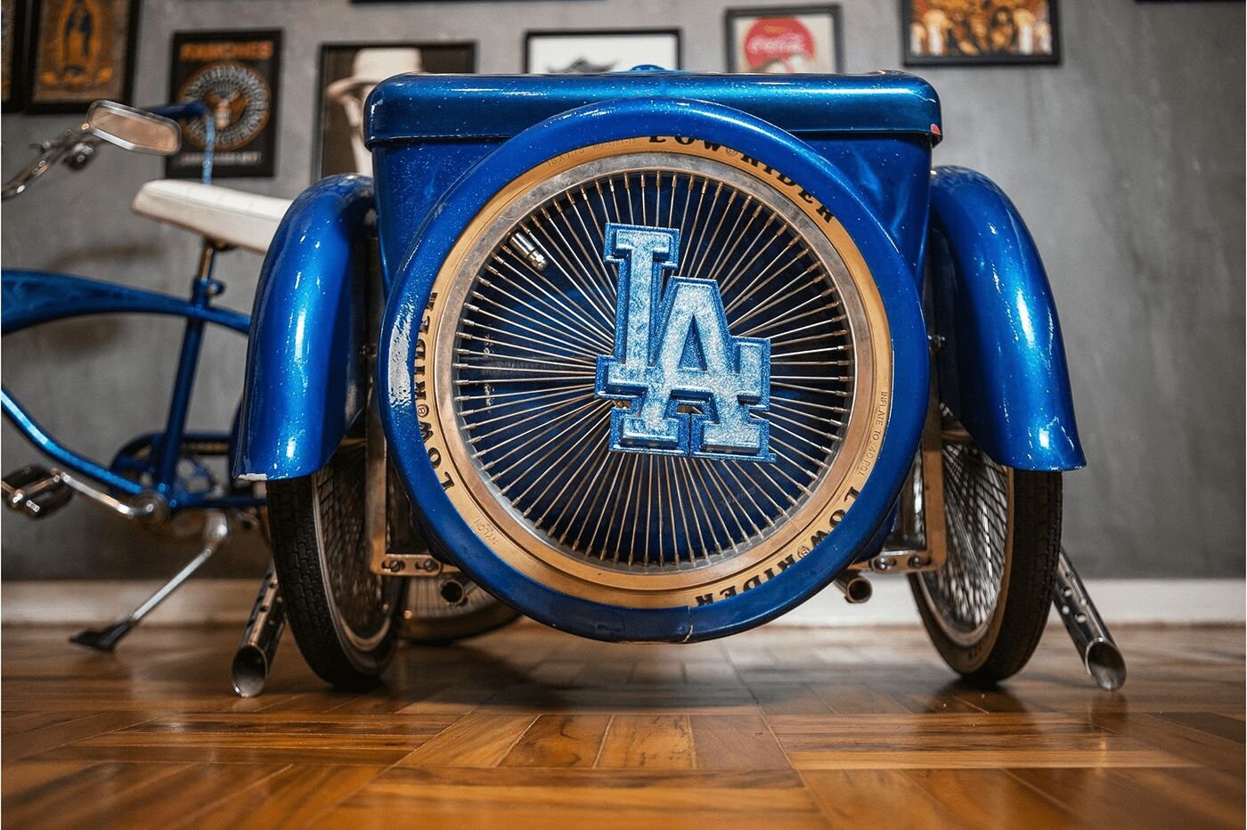 A blue lowrider bike with an LA logo on its wheel cover